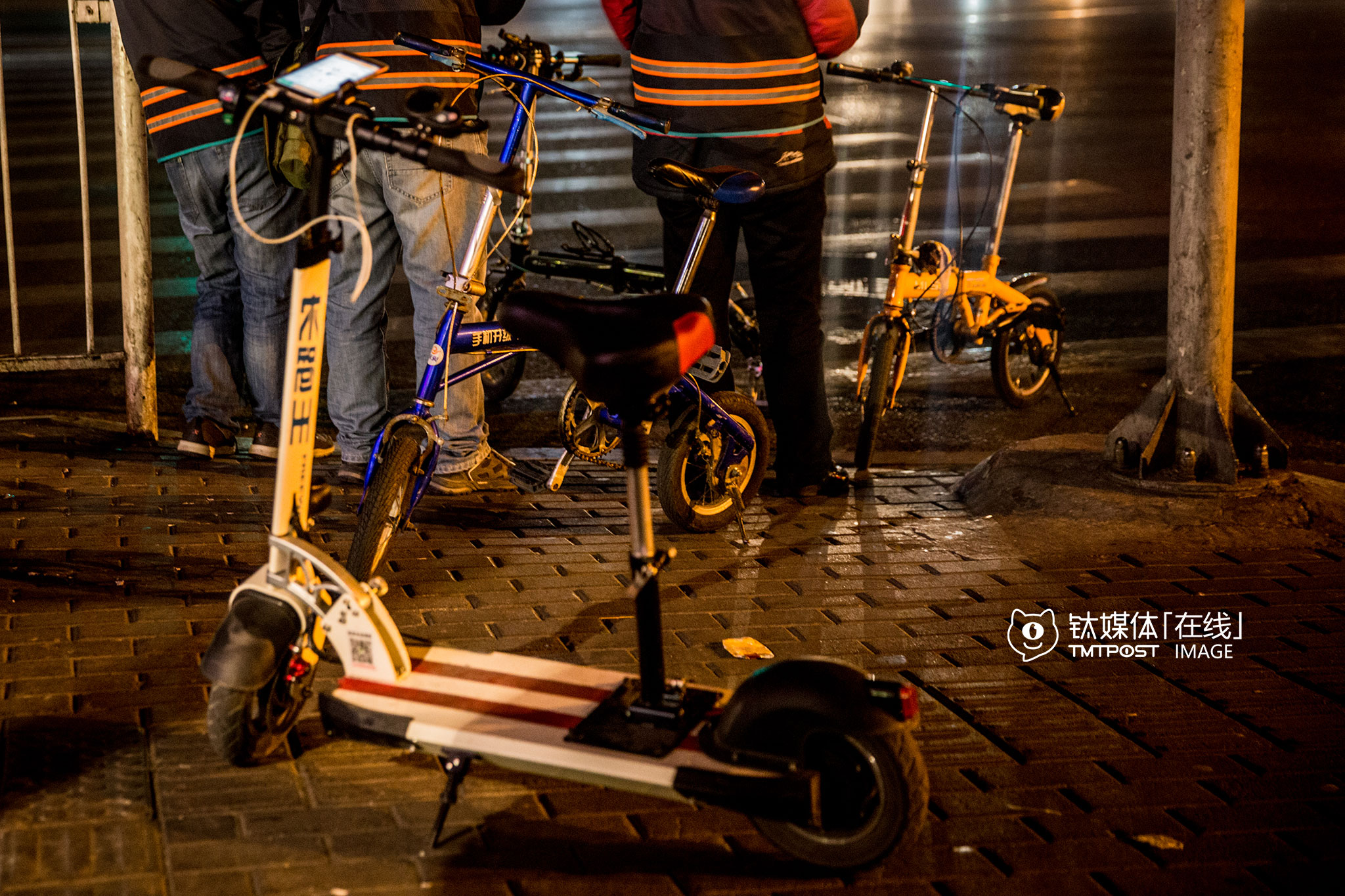 3月16日凌晨2:22，北京三里屯，等待订单的代驾。电动滑板车、自行车，是他们最重要的代步工具，接到订单后他们会把代步工具放到客人汽车的后备箱，以便到达目的地后离开。如果去到比较偏僻的地方，打不到车或者舍不得花钱打车，就只能靠这些代步工具回到四环，再坐夜班公交车，如果电动滑板车没电了，那就只剩下推着走这个办法了。