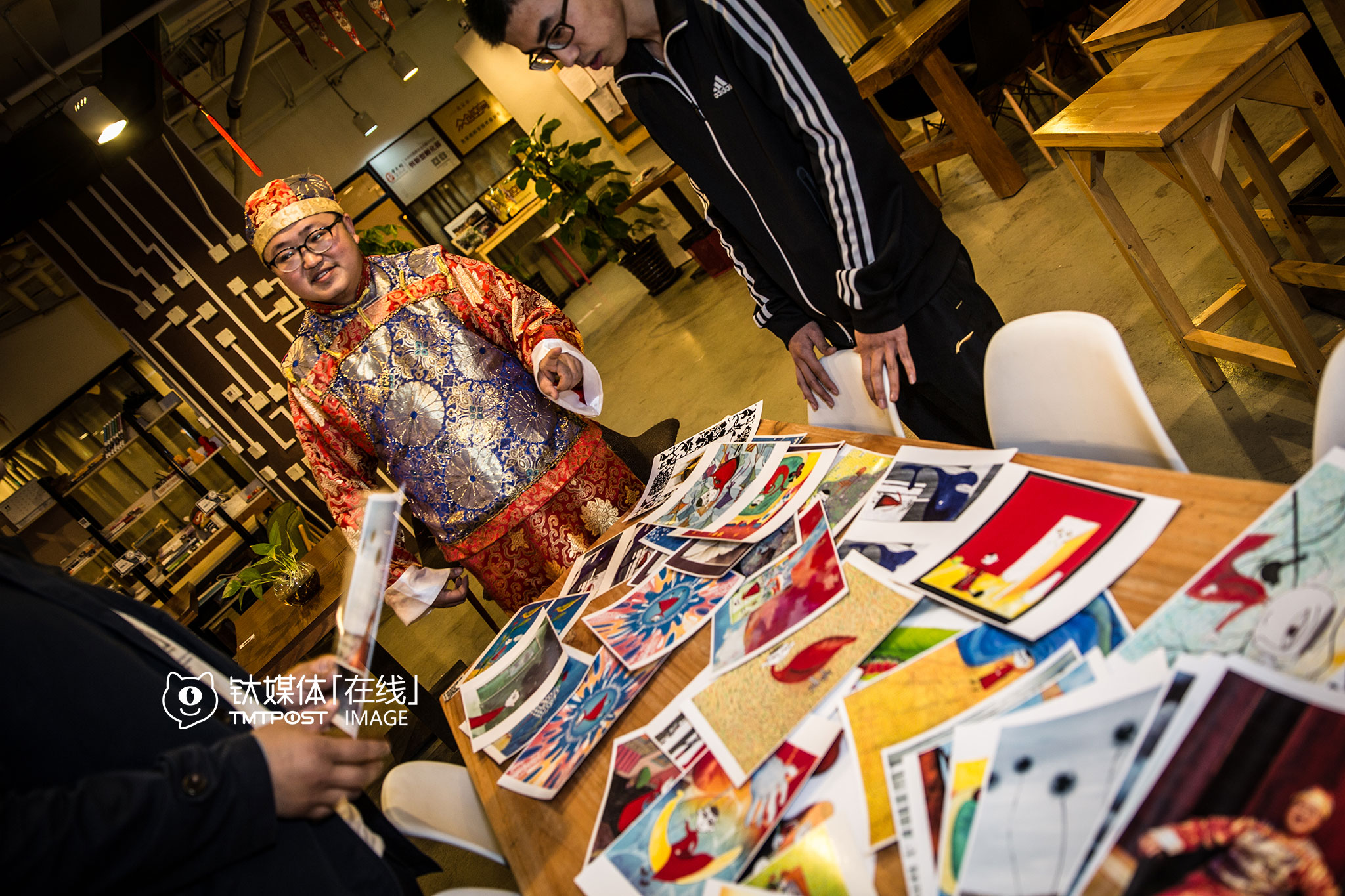 吴建辉在咖啡馆向别人介绍自己的漫画，这些颇具云南民俗风的作品，引起了不少人的兴趣，“我在打磨剧本，有些眉目了，现在就想找人一起拍出来，一起来让更多人知道。”