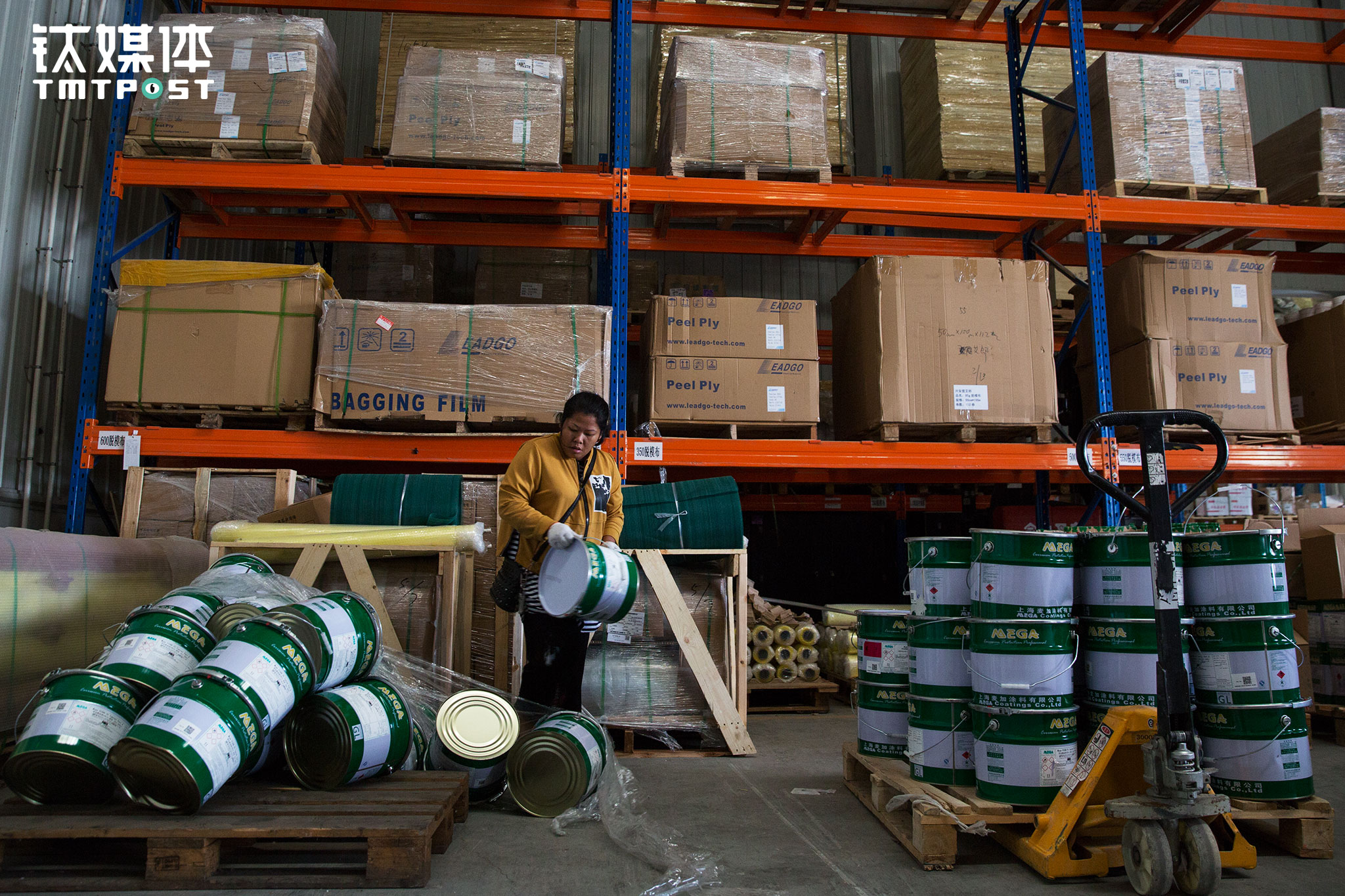 金强在外装货，王静在货主仓库里负责清点。货主的叉车不小心把货放倒了，仓库里没工人，王静帮着把这些装着油漆的筒子重新累起来。