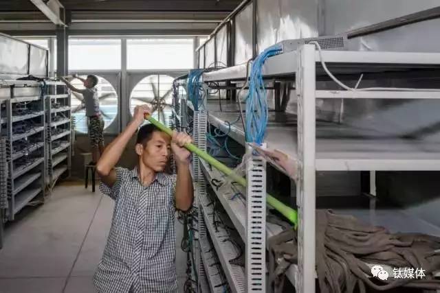 比特大陆矿池的一位清洁员正在用拖把清洁放置机器的架子