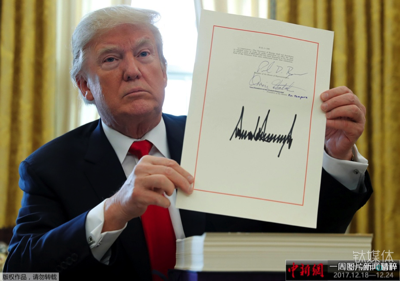 当地时间2017年12月22日，美国华盛顿，美国总统特朗普在白宫的椭圆形办公室签署1.5万亿美元税改法案，此乃美国最近逾30年来最大规模减税行动。图片来源：中新网