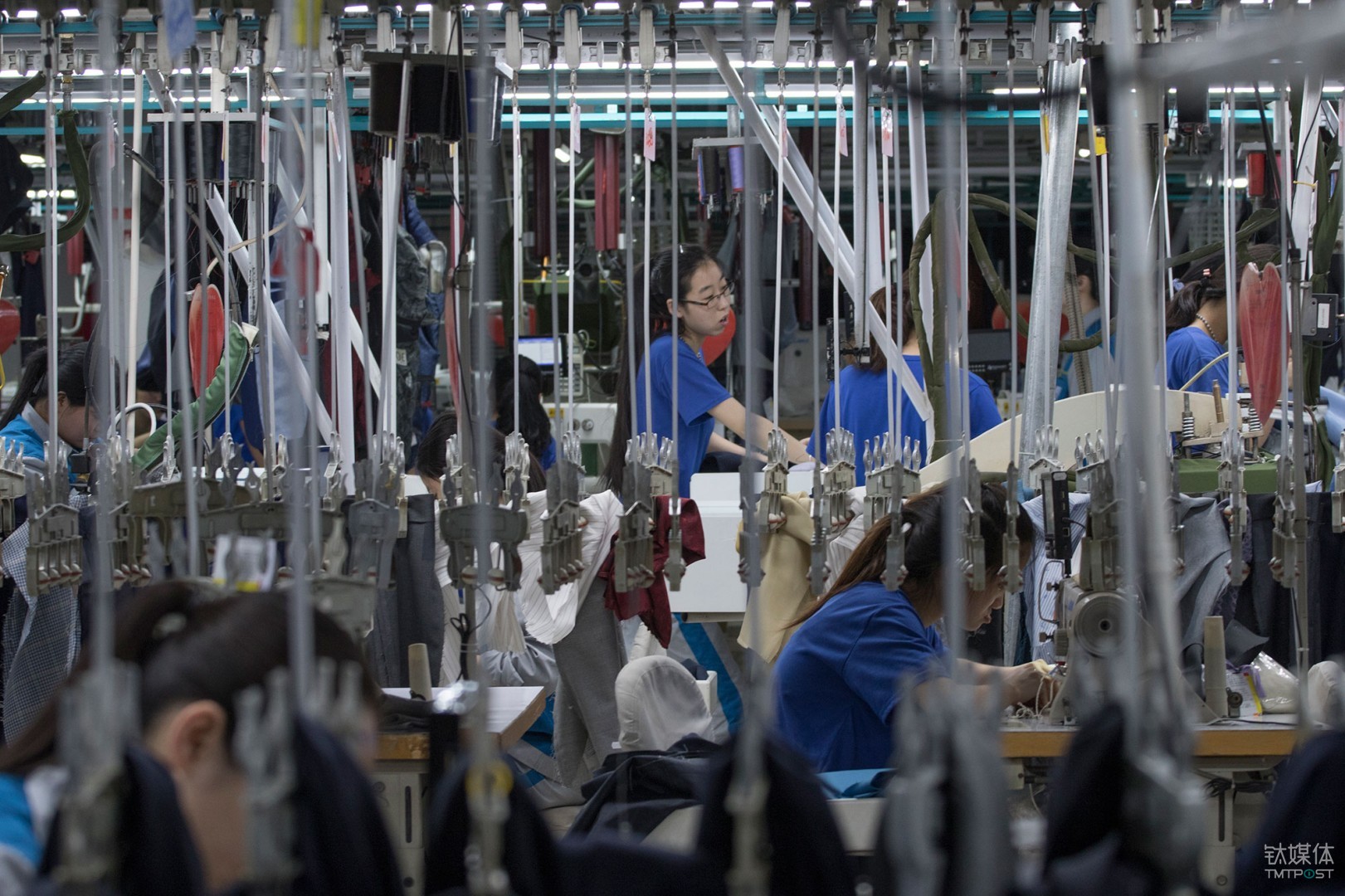 悬挂的青春。山东青岛，酷特智能车间的西服定制生产线，年轻女工在挂钩间工作。