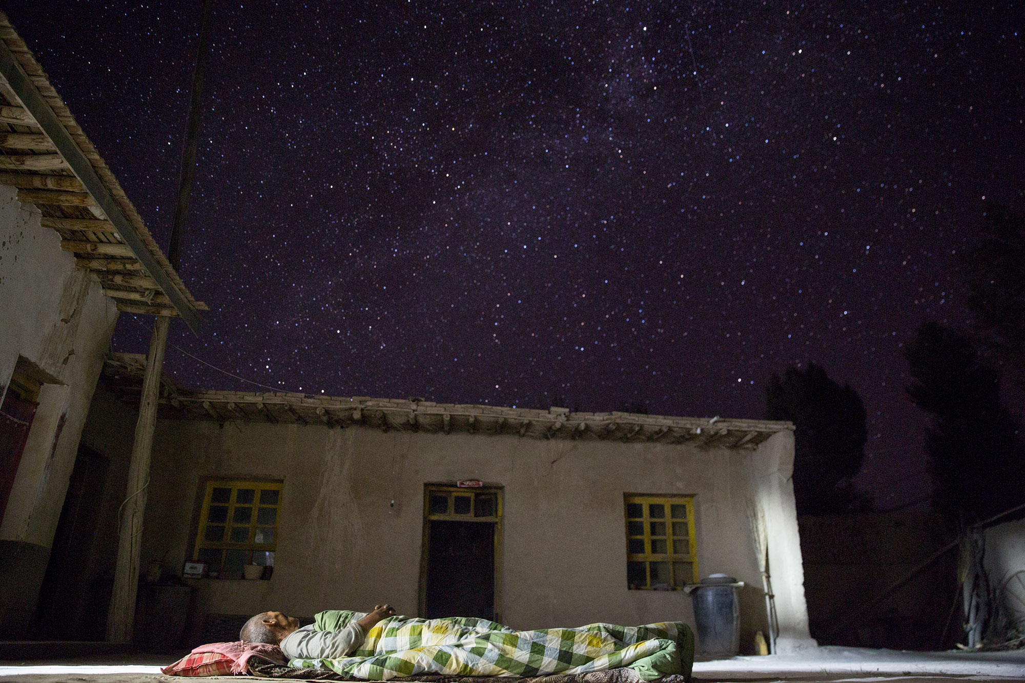 贫穷与富有。甘肃民勤，低保户李红善睡在自家简陋的院子里，仰面是浩瀚的星空。