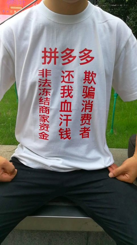 白色的t恤上用大红色印着"拼多多,欺骗消费者,还我血汗钱,非法冻结