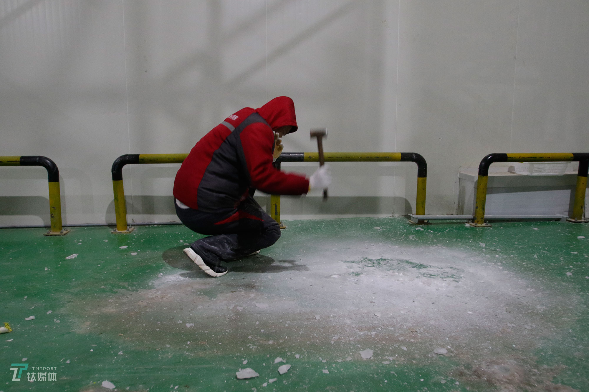 冷库通风系统滴下的水，在-18℃的低温中迅速凝结成冰，为了防止拣货员摔倒，一名冷库工人用锤子凿冰清理地面。