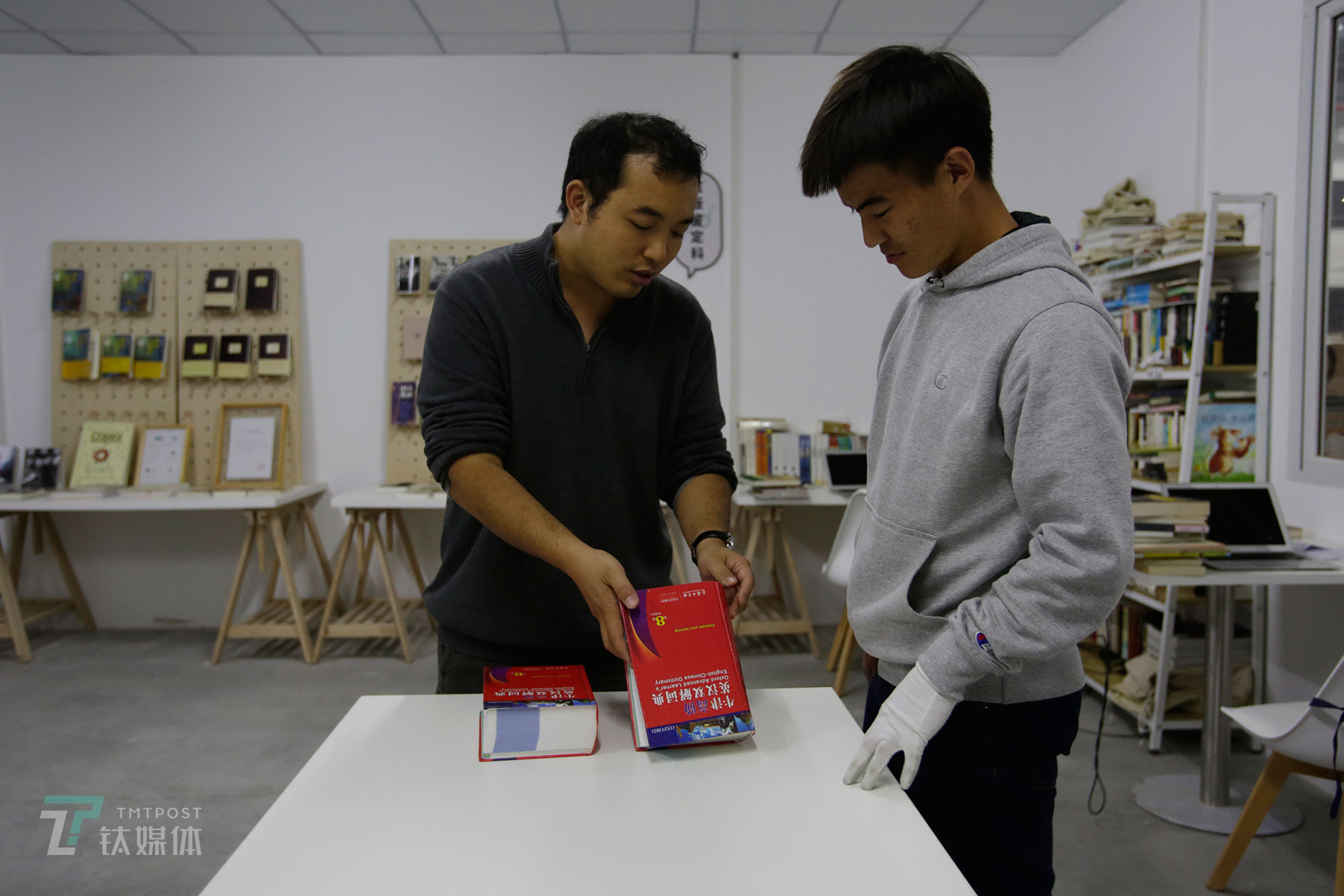 多抓鱼正盗版鉴定负责人杨玉擎拿着两本英汉词典给同事做正盗版鉴定培训。杨玉擎日常负责正盗版鉴定、收集正盗版数据库和正盗版鉴定培训。&ldquo;我们3个月才能培养出一个进行高难度正盗版鉴定的审核员&rdquo;。杨玉擎告诉钛媒体《在线》，他们团队在不断总结盗版书的各种特征，&ldquo;盗版特征数据化是一项很重要的工作，这样能让审核员们更快掌握如何识别盗版书。&rdquo; （陈拯 摄）