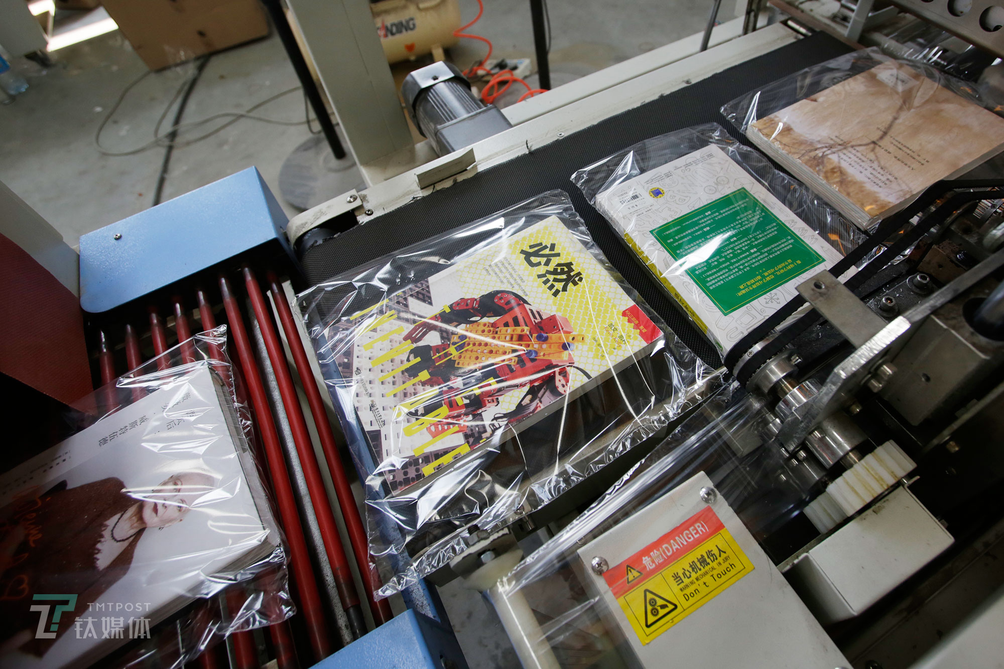 消毒完毕的书会被送上塑封机进行包装，这也是一本二手书在多抓鱼翻新工厂经历的最后一道工序。（陈拯 摄）