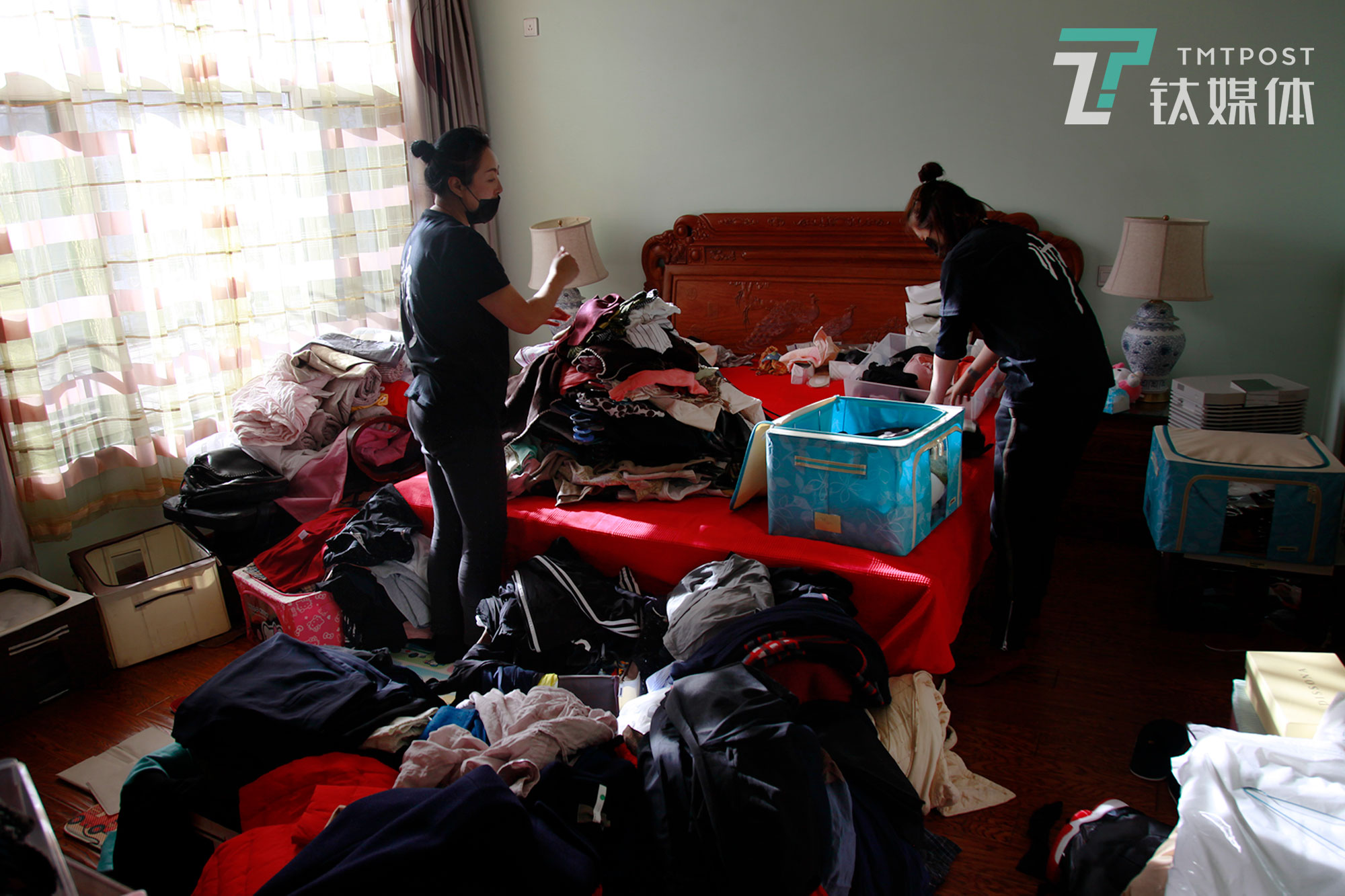 整理师将房主衣服全部从衣橱拿出来，堆放在床上。