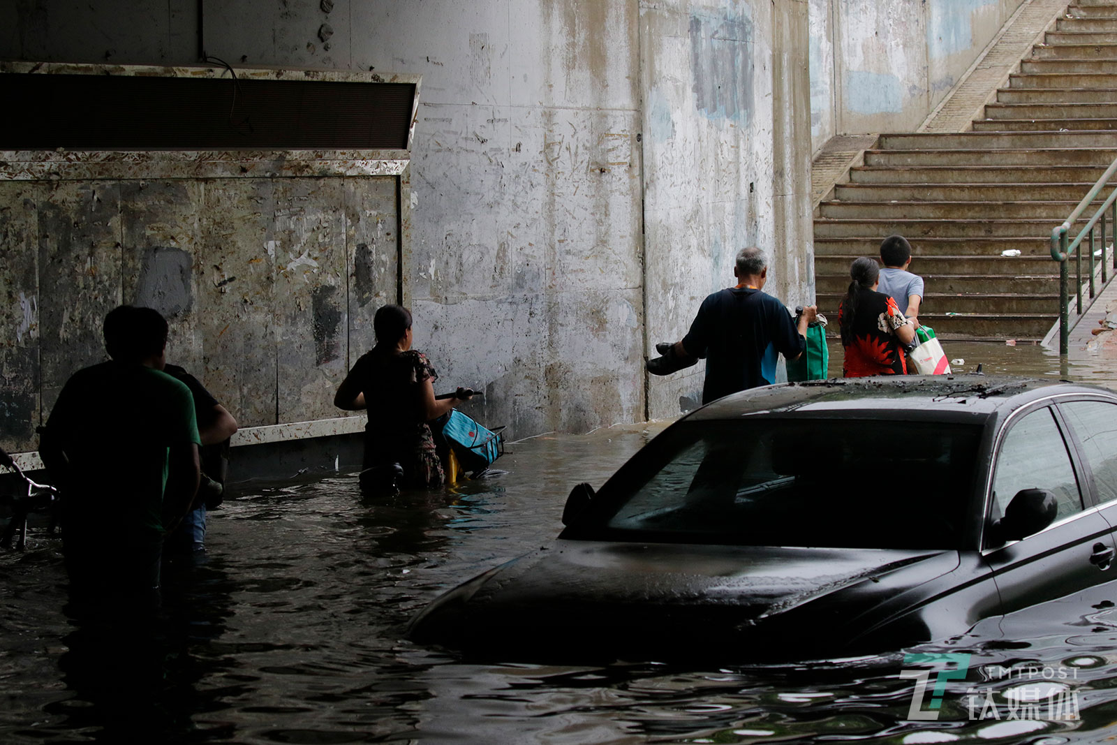 【蹚水】7月16日，北京昌平区回龙观育知东路城铁桥下，强降雨后形成了最深超两米的积水，行人涉险蹚水穿过桥下的人行道。