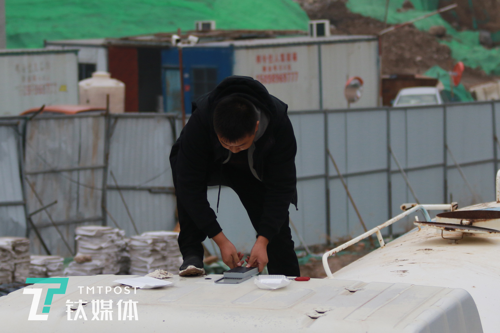 机械指挥官销售员陈兵在一台洒水车车顶安装智能终端。