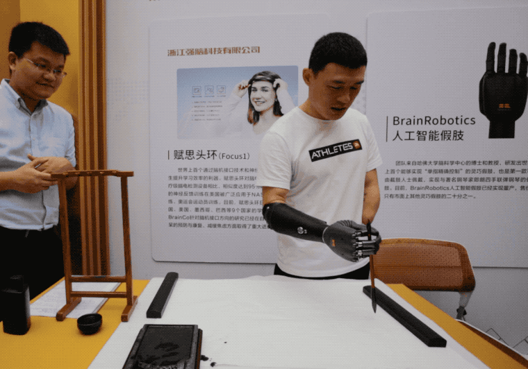 杭州,一场科技展会上,倪敏成穿戴着智能假手写毛笔字。他说,这只假手会为他的家人和朋友带去慰藉。