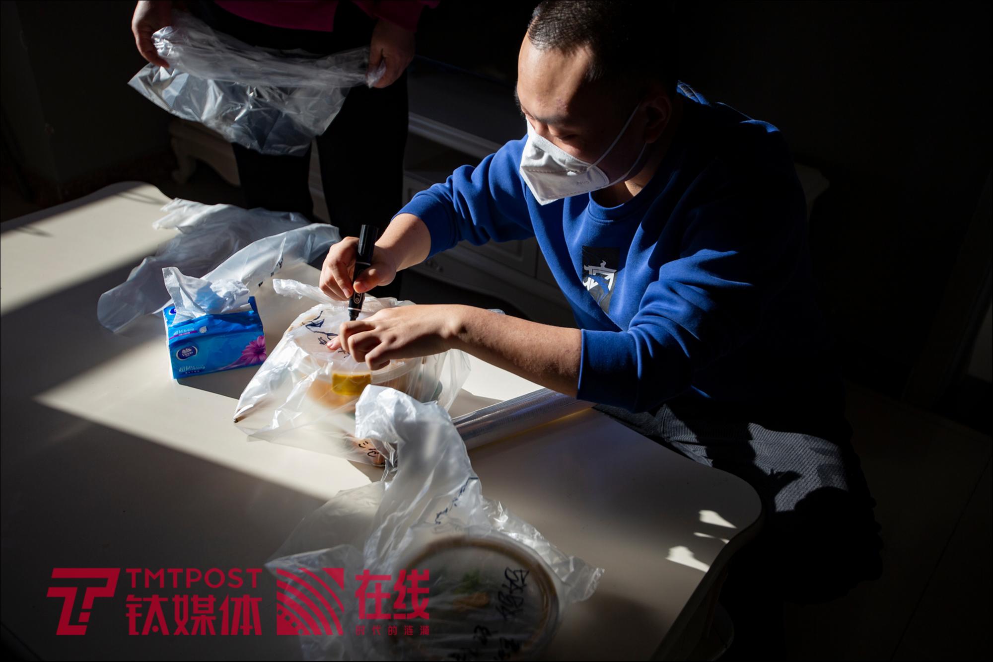 河北燕郊，朱远康在准备送往医院的午餐袋子上写下孩子的名字。