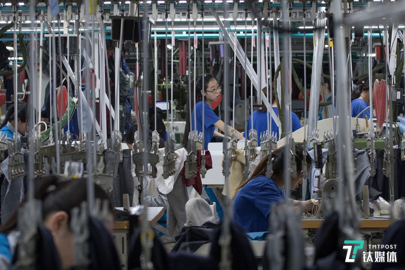 悬挂的青春。山东青岛，酷特智能车间的西服定制生产线，年轻女工在挂钩间工作。