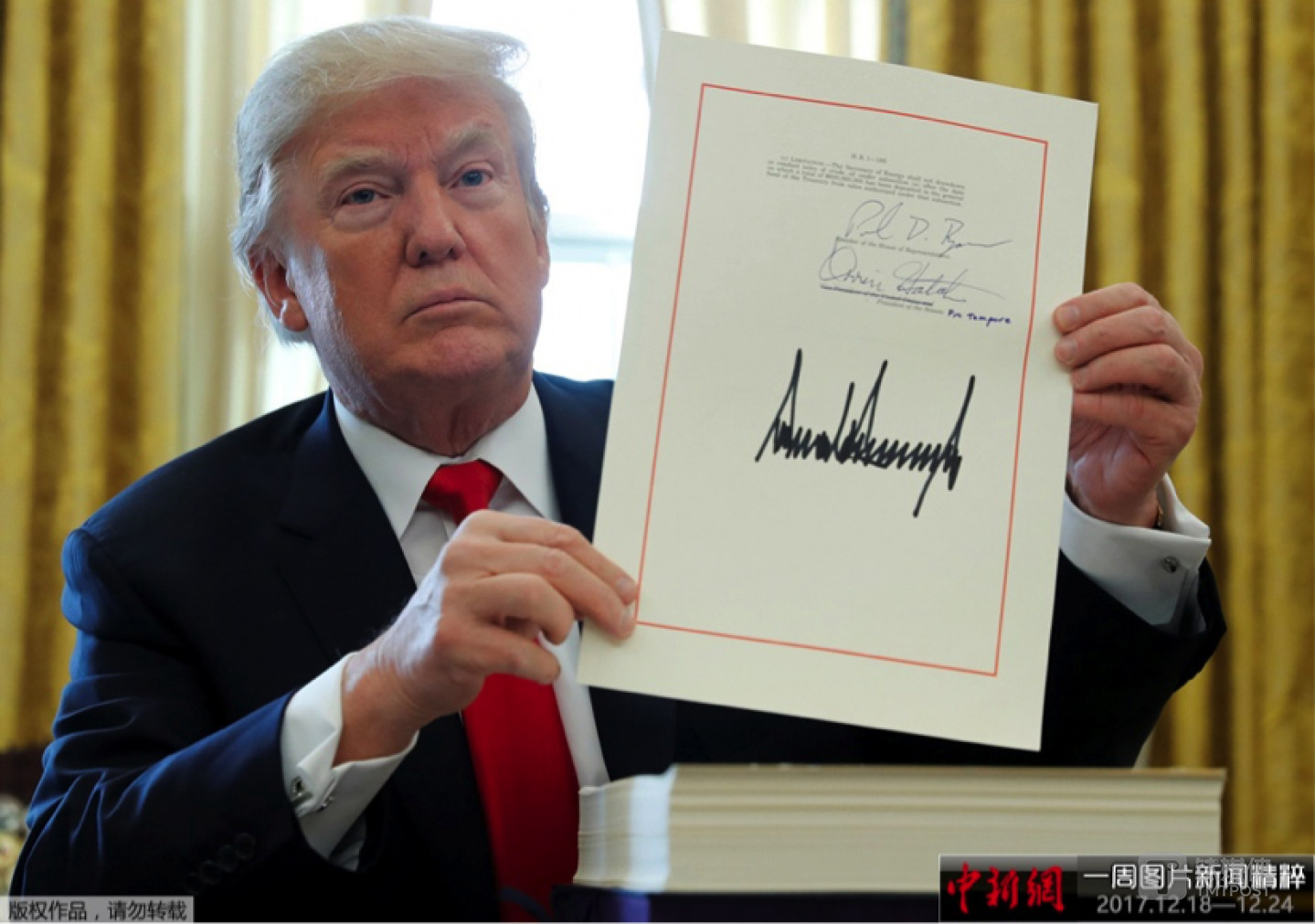 当地时间2017年12月22日，美国华盛顿，美国总统特朗普在白宫的椭圆形办公室签署1.5万亿美元税改法案，此乃美国最近逾30年来最大规模减税行动。图片来源：中新网