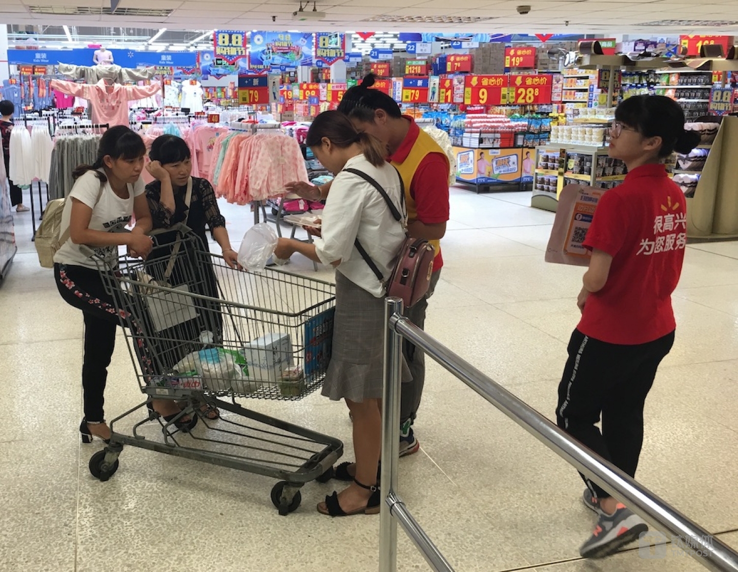 沃尔玛共工作人员正在指导消费者使用扫码购